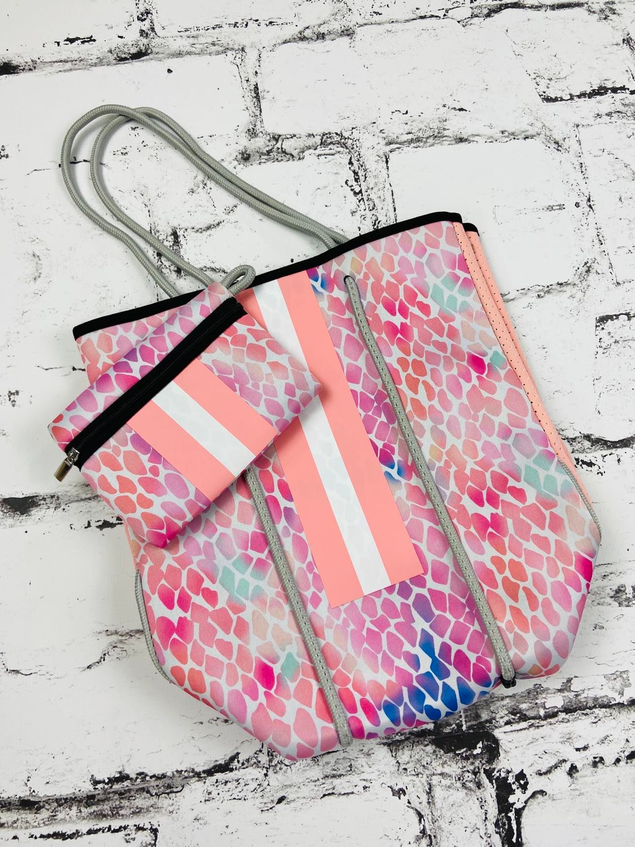 This neoprene tote is the ultimate combination of luxury and functionality. Made of durable, stain-resistant neoprene with woven corded rope accents, this lightweight bag features a magnetic snap closure, removable hard bottom liner, and a convenient zip pouch. Use it year-round and wash it easily with mild soap. Perfect for trendy and stylish people who need a versatile and practical bag for any occasion!